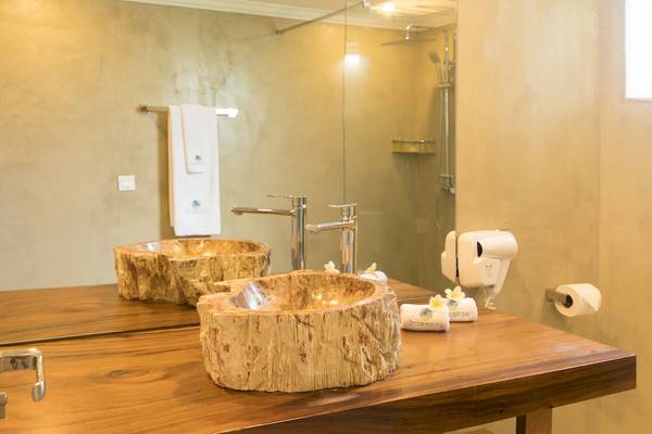 Badezimmer im Seasense Boutique Hotel mit runden Baumstammwaschbecken und Glasdusche.