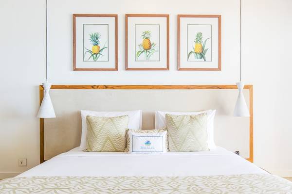 Bett im Seasense Boutique Hotel & Spa mit drei Ananas-Bildern an der Wand.