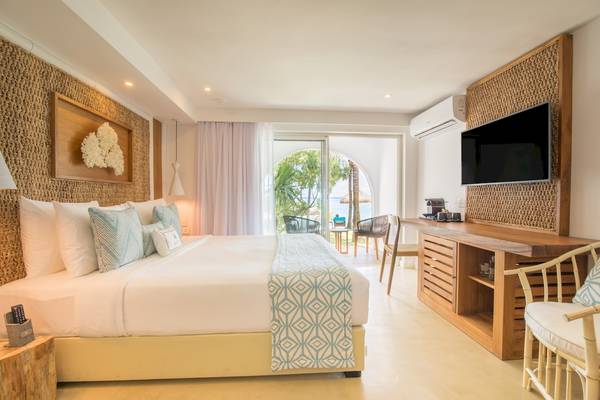 Schlafzimmer mit Doppelbett, Fernseher und Blick auf den Strand im Seasense Boutique Hotel & Spa.