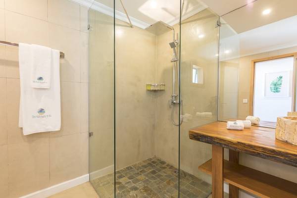 Dusche im Badezimmer des Seasense Boutique Hotel & Spa mit Glastür und Steinboden.