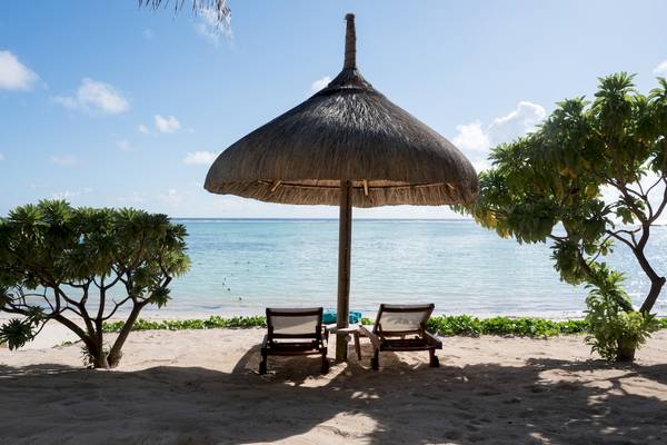 Strand mit Liegen unter einem Strohhut in der Nähe des Meeres