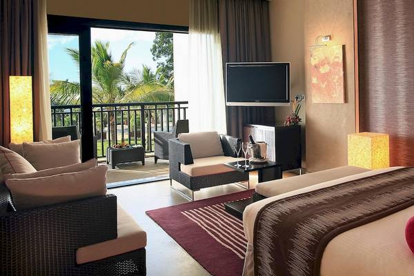 Innenansicht eines Hotelzimmers mit Blick auf einen Balkon und Palmen