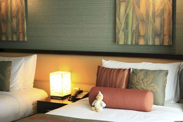 Doppelbett im Zimmer des InterContinental Resort Mauritius mit Dekokissen und Nachttischlampe.