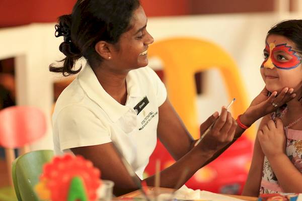 Eine Frau malt ein Gesicht eines Maedchens im InterContinental Resort Mauritius, einem IHG Hotel.
