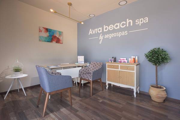 Innenansicht des Avra Beach Spa mit Möbeln, Pflanzen und einer Wandbeschriftung.