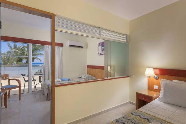 Innenansicht eines Zimmers im Avra Beach Resort Hotel & Bungalows mit Blick auf das Meer und eine Terrasse.