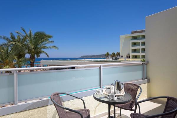 Balkon mit Meerblick im Avra Beach Resort Hotel & Bungalows mit Tisch, Tassen und Kaffeekanne.