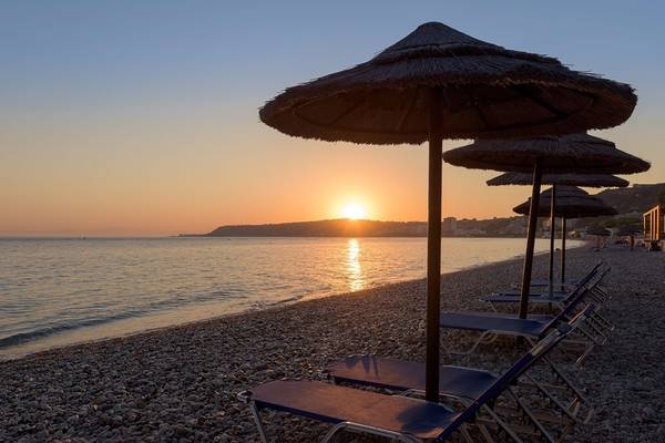 Strand mit Liegen und Sonnenschirmen bei Sonnenuntergang