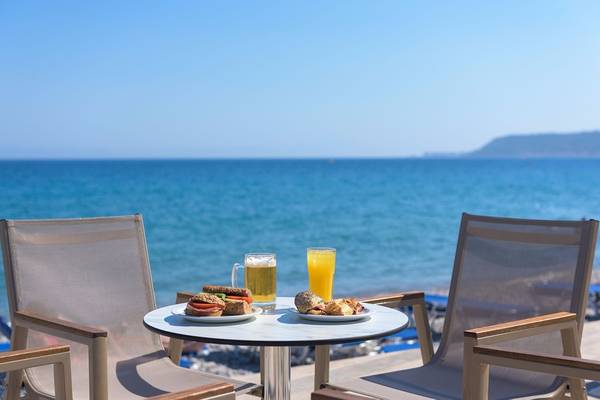 Avra Beach Resort Hotel Terrasse mit Meerblick, Frühstücksplatten, Bier und Orangensaft.