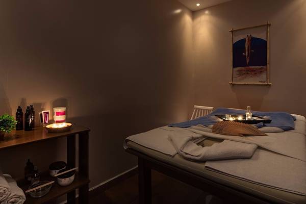 Massageraum im Avra Beach Resort Hotel & Bungalows mit einem Bett, Kerzen, Pflanzen und einer Wanddekoration.
