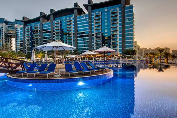 Pool-Ansicht im Dukes The Palm, a Royal Hideaway Hotel mit Lounge-Stühlen und Sonnenschirmen.