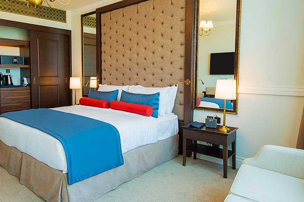 Zimmer im Dukes The Palm, a Royal Hideaway Hotel mit Bett, Nachttischen und Spiegel.