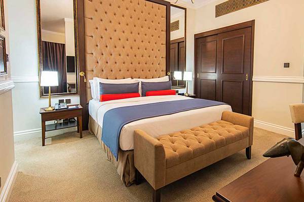 Das Hotelzimmer von Dukes The Palm, a Royal Hideaway Hotel, mit einem großen Bett, einem gepolsterten Kopfteil und einer Kommode.
