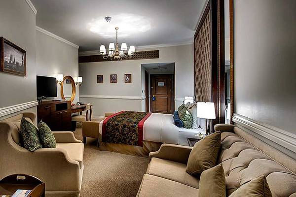 Innenansicht einer Suite im Dukes The Palm, a Royal Hideaway Hotel mit Bett, Wohnzimmerbereich und Fernseher.