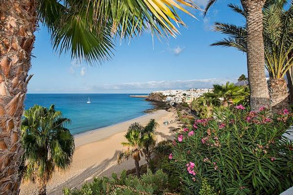 Strand des IFA Altamarena by Lopesan Hotels mit blauem Meer, Palmen und weißen Gebäuden.
