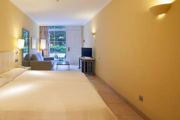 Zimmer im IFA Altamarena Hotel mit zwei Betten, gelben Wänden und einem Fernseher.