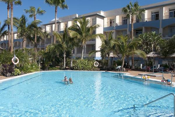 Ein Swimmingpool vor dem Hotel IFA Altamarena by Lopesan Hotels mit zwei Personen im Wasser.
