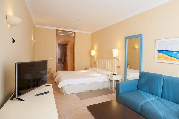 Hotelzimmer im IFA Altamarena mit einem Bett, Fernseher, Sofa und einem Bild an der Wand