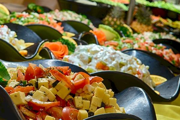 Ein Buffet mit verschiedenen Obstsalaten und Gemüseplatten, darunter ein großer Ananas-Schnitt.