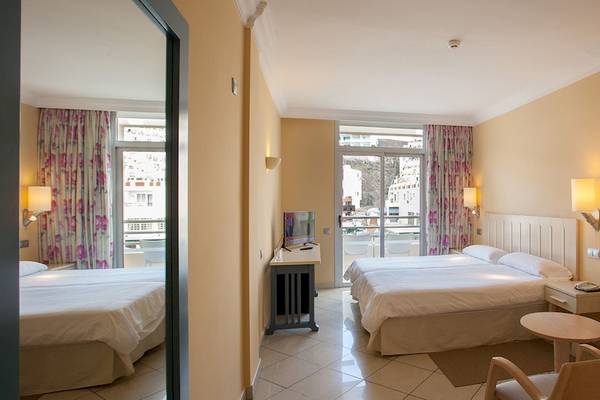 Zimmer im IFA Altamarena by Lopesan Hotels mit zwei Betten, Schreibtisch, Fernseher und Balkon.