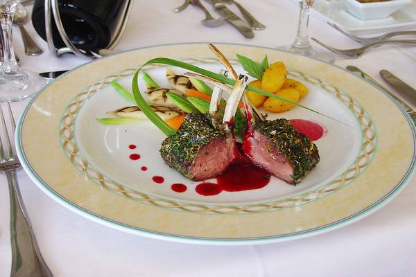 Ein gegrilltes Lammkarree mit Kräutern auf einem dekorativ bedruckten Teller im Rodos Palladium Hotel.
