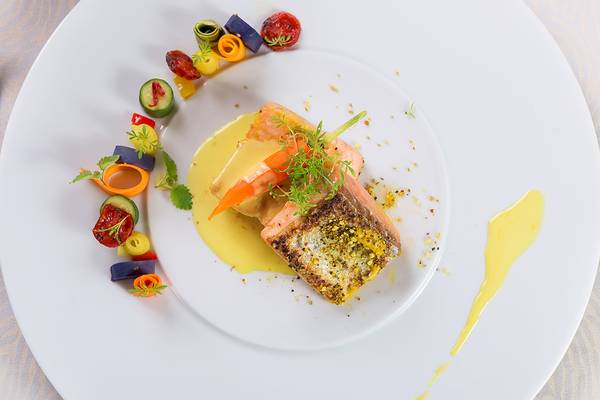 Gegarter Lachs auf weißem Teller mit Gemüse und Sauce