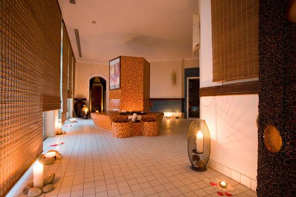 Eingangsbereich des Rodos Palladium Leisure & Wellness mit Fliesenboden, dekorativen Kerzen und einer gefliesten Wand.