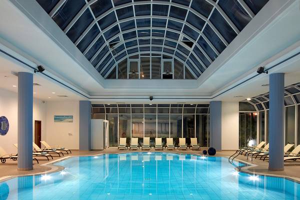 Ein Pool mit Liegen und einem Glaskuppeldach im Rodos Palladium Leisure & Wellness Hotel.