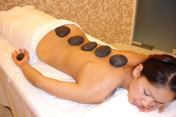 Frau im Hotel mit Steinen auf dem Rücken, die eine Massage genießt.
