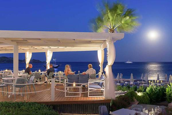 Nachtansicht der Hotelterrasse mit Gästen, Vollmond und Meer