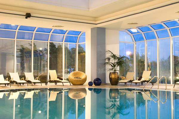 Pool-Loungebereich im Rodos Palladium Leisure & Wellness mit blauem Wasser und Lounge-Liegen.