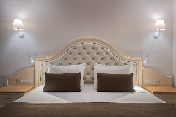 Hotelzimmer mit Bett, Kissen und Wandlampen im Rodos Palladium.
