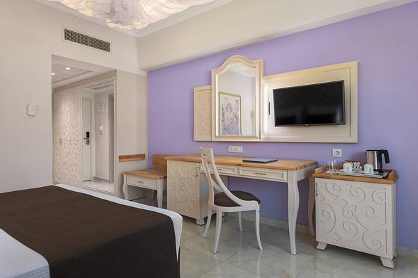 Hotelzimmer im Rodos Palladium Leisure & Wellness mit einem Bett, Schreibtisch und Fernseher.