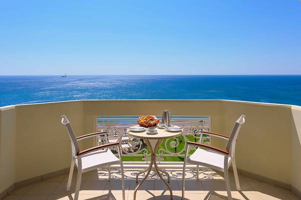 Ein Balkon mit Meerblick im Rodos Palladium Hotel, mit zwei Stühlen, einem Tisch und einem Kaffeeservice.
