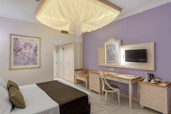 Hotelzimmer im Rodos Palladium Leisure & Wellness mit Bett, Schreibtisch, Gemälde und Fernseher.