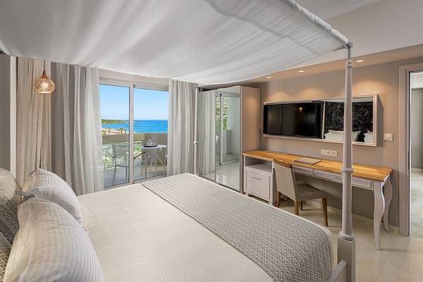 Ein Bett mit Meerblick im Rodos Palladium Leisure & Wellness Hotel, umgeben von weißen Vorhängen und einem Baldachin.