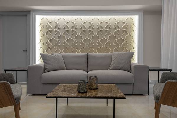 Wohnzimmer mit grauer Couch, marmorfarbenem Tisch und gemusterter Wand