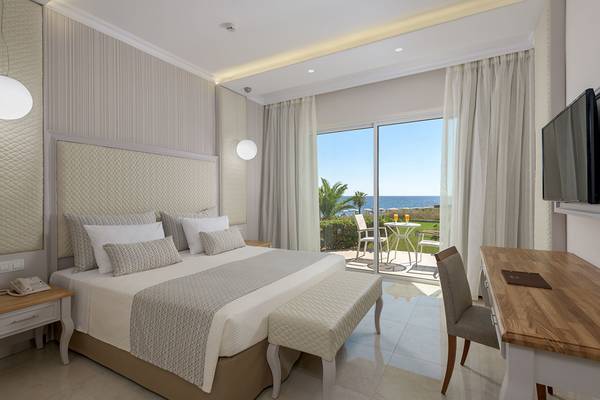 Hotelzimmer mit Meerblick, Bett, Balkon und Schreibtisch.