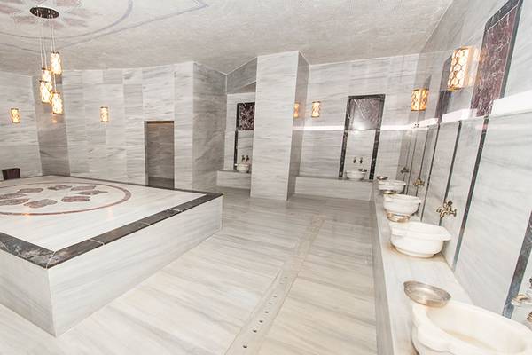 Innenbereich der Sauna im Seaden Sea Planet Resort & Spa mit weißen Marmorwänden und mehreren Waschbecken.