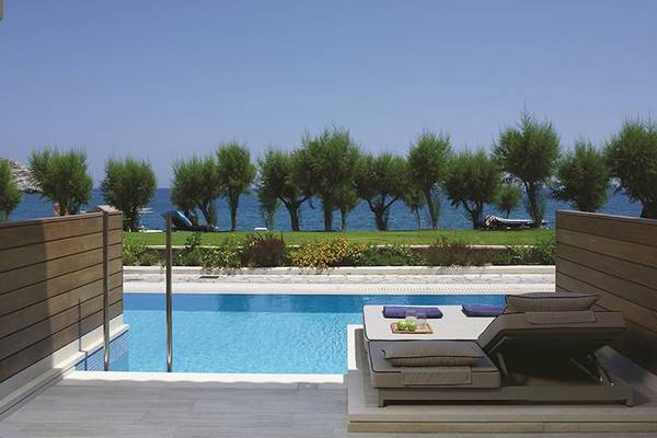 Pool-Loungebereich im Atlantica Imperial Resort & Spa mit Blick auf das Meer und Bäume.