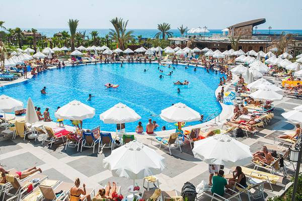 Überblick über den Poolbereich des Seaden Sea Planet Resort & Spa mit vielen Gästen und Sonnenschirmen.