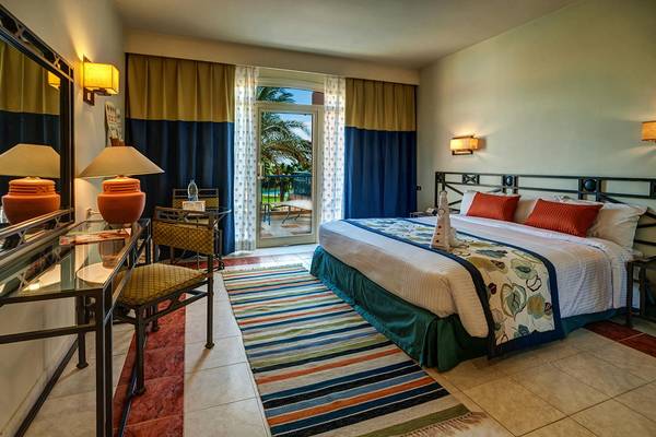 Ein Hotelzimmer im LABRANDA Club Paradisio El Gouna mit einem großen Bett, einer Sitzecke und einem offenen Balkon.