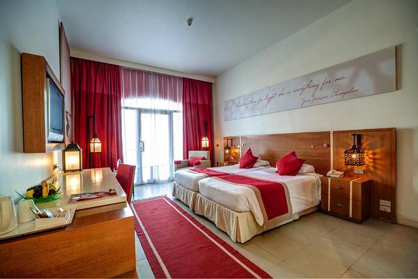 Hotelzimmer im LABRANDA Club Paradisio El Gouna mit zwei Betten, Tisch, Fernseher und roter Dekoration.