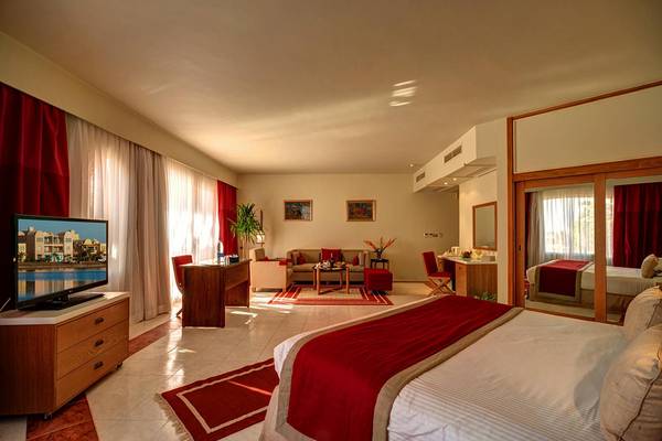 Schlafzimmer im Labranda Club Paradisio El Gouna Hotel mit Doppelbett, Fernseher und Wohnzimmermöbeln.