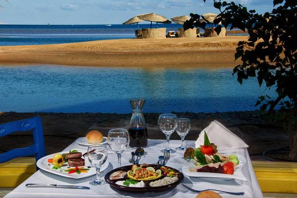 Ein Tisch am Strand mit Aussicht auf das Meer, auf dem eine Mahlzeit serviert ist.
