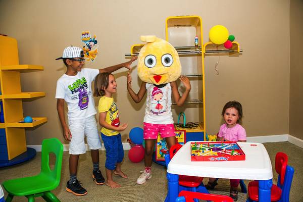 Ein Kinderspielzimmer im Hotel LABRANDA Club Paradisio El Gouna mit einem gelben Spielzeugvogel, drei Kindern und einer kleinen, die ein Brettspiel spielt.