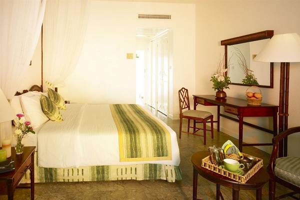 Schlafzimmer im Sarova Whitesands Beach Resort & Spa mit Bett, Tisch, Stühlen und Dekor.