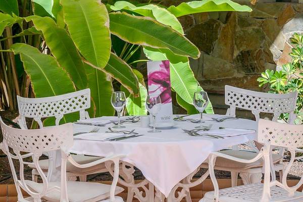 Außentisch im Barcelo Corralejo Bay Hotelgarten mit gedecktem Tisch und Weinglas