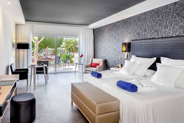 Hotelzimmer des Barcelo Corralejo Bay mit Doppelbetten, Fernseher und Terrasse.