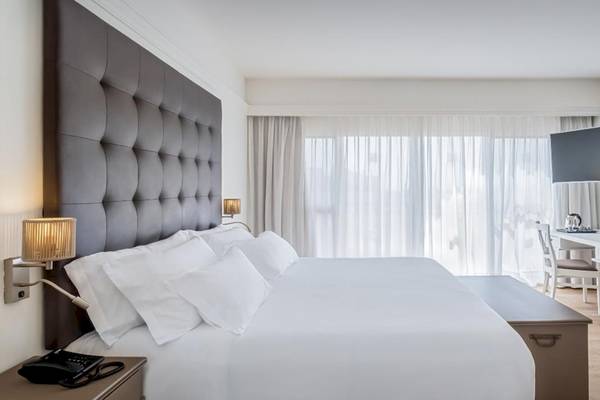 Hotelzimmer im Barcelo Corralejo Bay mit einem großen Bett, einem Schreibtisch und einem Fernseher an der Wand.